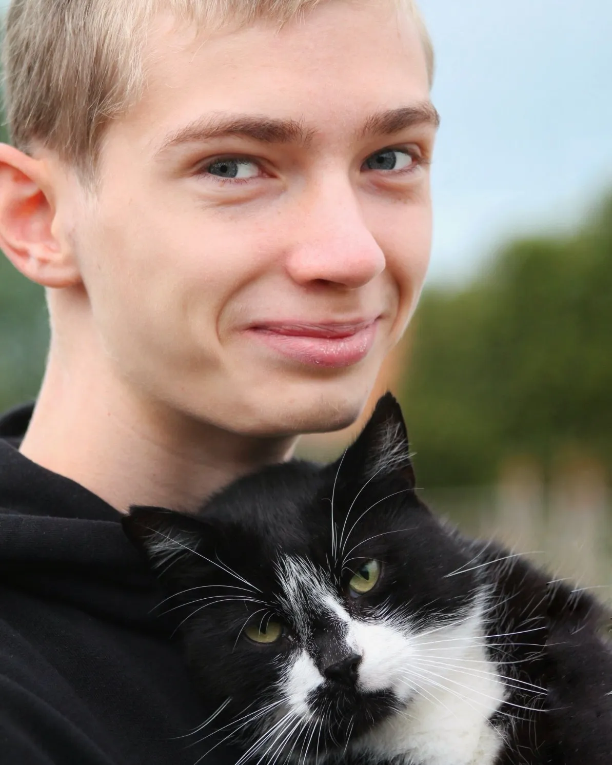 Tobi, Pferdewirt-Azubi, im Portrait mit einer Hofkatze